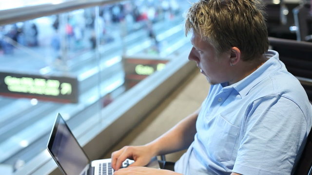 Young businessman using laptop at airport