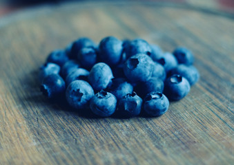 Closeup of a pile of blueberries against a worn wooden background (shallow DOF, selective focus), retro style