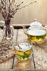 Eucalyptus tea with leaves in transparent cup and teapot on vintage wooden table background. Rustic...