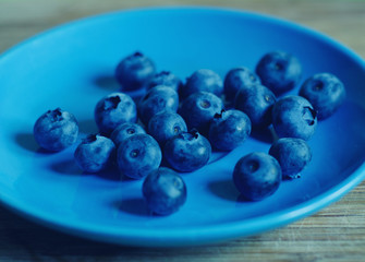 Closeup of a pile of blueberries on a blue dish (shallow DOF, selective focus), retro style