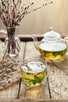 Eucalyptus tea with leaves in transparent cup and teapot on vintage wooden table background. Rustic style