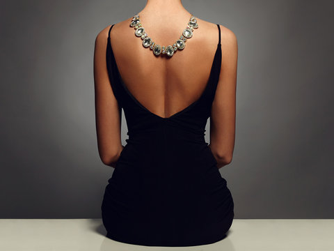 beautiful back of young woman in a black sexy dress.Girl with a necklace