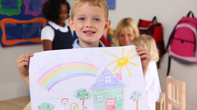 Preschool boy holding up artwork