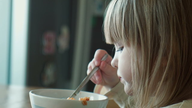 The little girl eats at a table