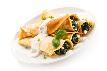 Crepes with spinach and feta cheese on white background 