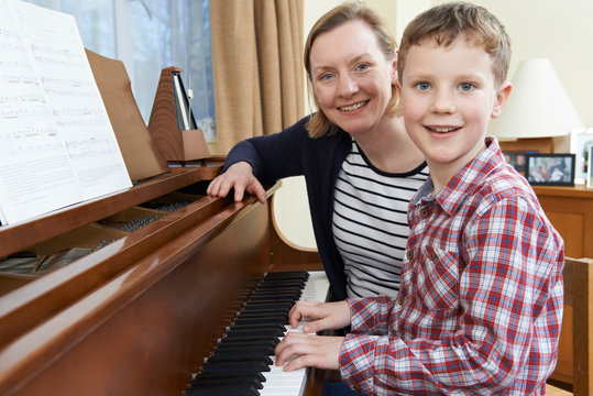 Boy With Music Teacher Having Lesson At Piano