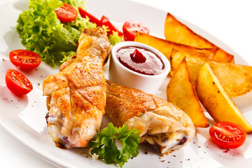 Grilled chicken legs with baked potatoes and vegetables