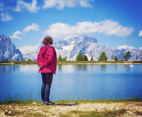 woman standing beside a clear mountain lake enjoying the view