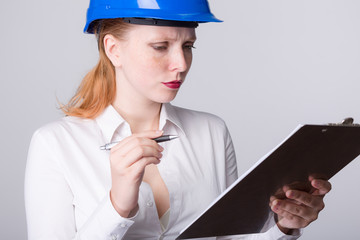 Junge Ingeneurin mit Schutzhelm denkt nach