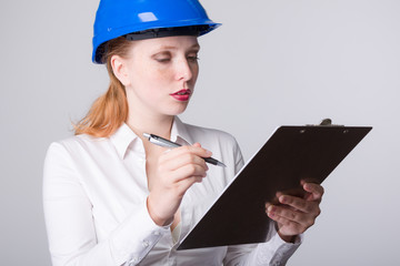 Junge Ingeneurin arbeitet gewissenhaft mit Schutzhelm