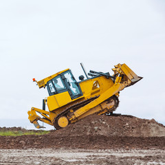 dirty Yellow bulldozer overcome ground barrier