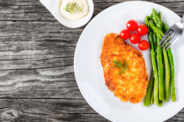 meat chop fried in tempura with asparagus and cherry tomatoes