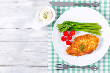 meat chop fried in tempura with asparagus and cherry tomatoes