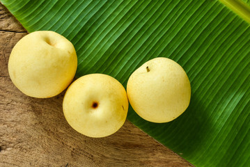 Three Chinese pears on green banana leaf and wood background