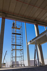 Painter is in action high up on scaffold with white color.