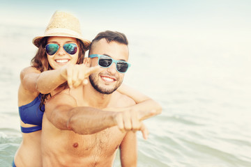 Obraz premium Happy couple pointing at the beach