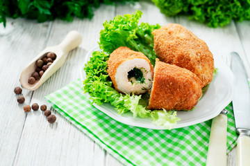 Ukrainian national dish , chicken Kiev  , cutlets of chicken meat in breadcrumbs with butter , dill, pepper and lettuce on a wooden background