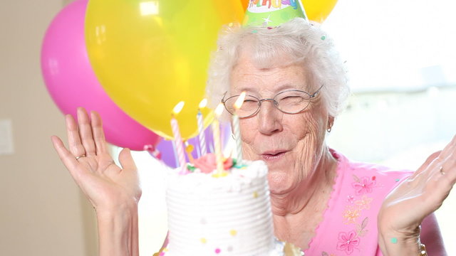 Senior woman blows out candles