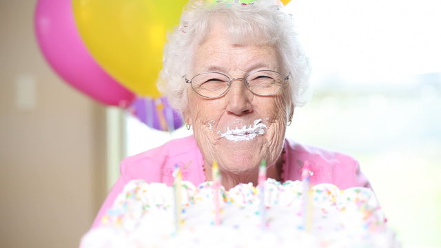 Senior woman takes bite of cake