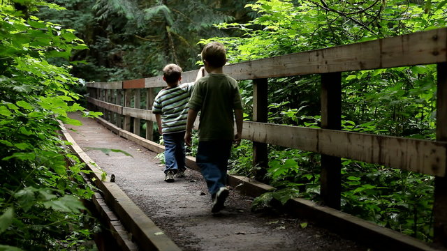Two young boys walk across bridge