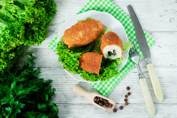 Ukrainian national dish , chicken Kiev  , cutlets of chicken meat in breadcrumbs with butter , dill, pepper and lettuce on a wooden background