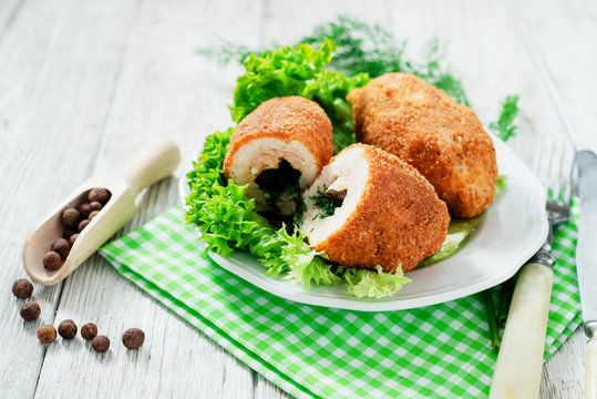 Ukrainian national dish , chicken Kiev  , cutlets of chicken meat in breadcrumbs with butter , dill, pepper and lettuce on a wooden background