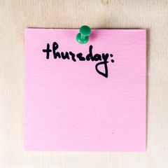 Thursday  note on paper post it pinned to a wooden board