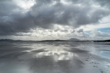 Beeindruckende Wolken spiegeln sich auf feuchtem Strand