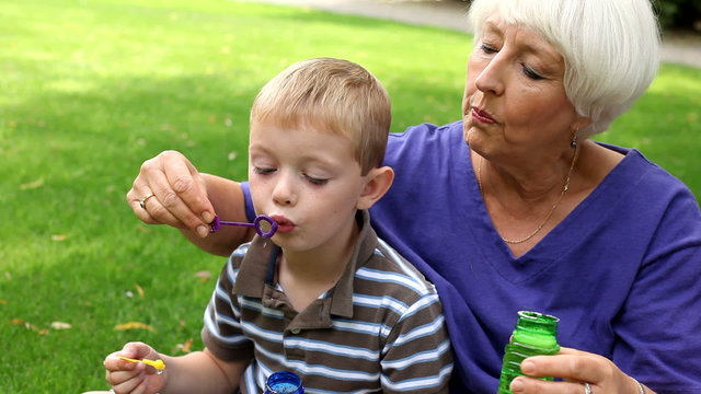 Senior woman blowing bubbles with children