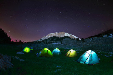 Illuminated yellow camping tent under stars at night - obrazy, fototapety, plakaty