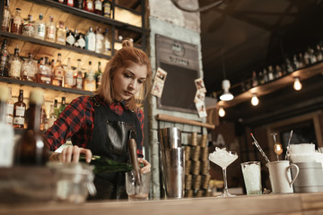Woman bartender making an alcohol cocktail at the bar