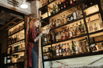 Bartender pulls out a bottle of alcohol from bar shelves