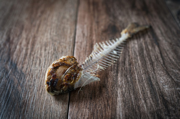 Close up of fish bone on rustic wooden background. Greed, hunger concept.