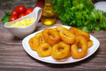 deep fried calamari with sauce and salad on a wooden background