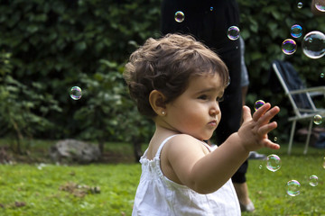 Girl playing with soap bubbles in the garden