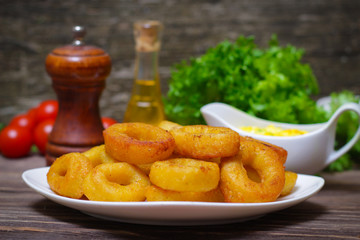 deep fried calamari with sauce and salad on a wooden background