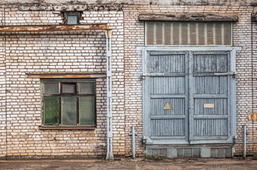 Fototapeta na wymiar old factory wall of white bricks with window and gate
