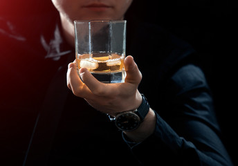 Vertical business man keeps the whiskey glass with ice in his hand