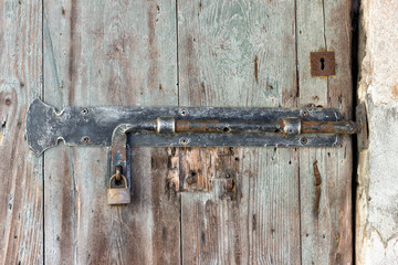 Old rusty latch on a wooden peeling door