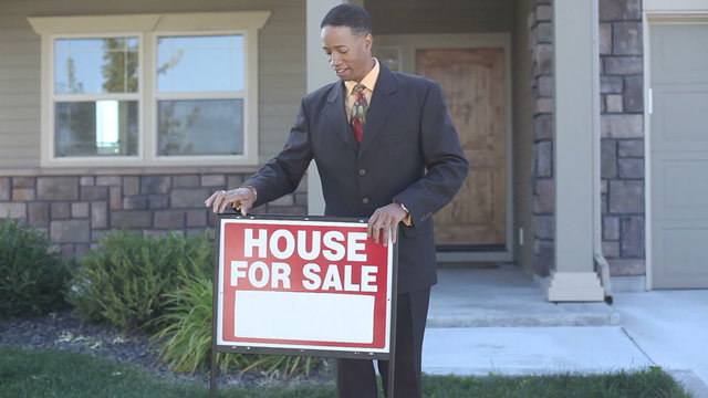 Realtor puts FOR SALE sign in front of home