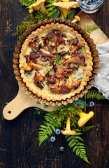 Quiche with chanterelle mushrooms and fresh savory on a wooden rustic table