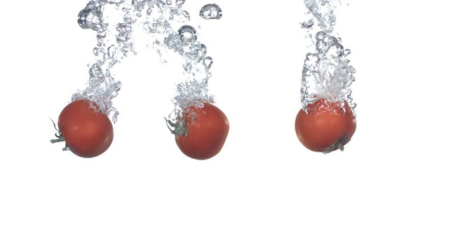 Tomatoes splashing into water, slow motion
