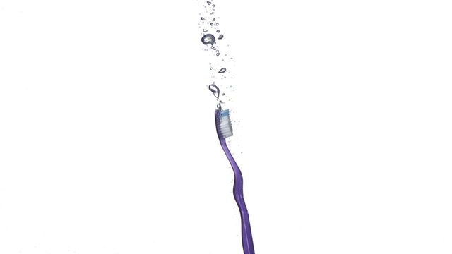 Toothbrush splashing into water, slow motion