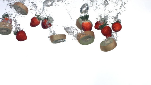 Kiwi and strawberries splashing into water