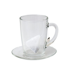 glass cup and saucer with tea bag on white background