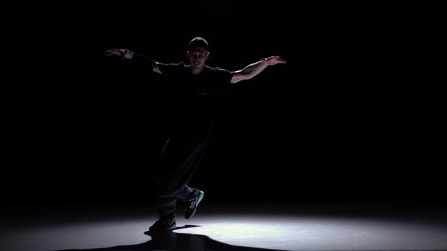 Stylish breakdance style dancer starts dance, on black, shadow, slow motion