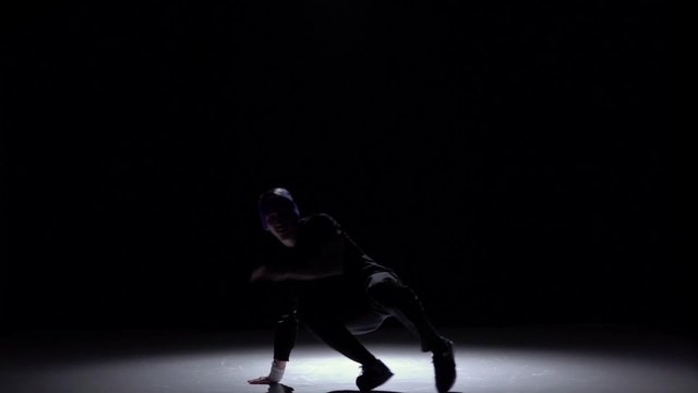 Handsome breakdance style dancer goes on dance, on black, shadow, slow motion