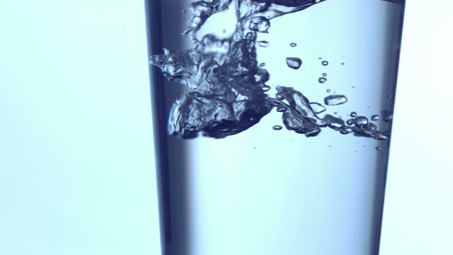 Water pouring into a glass, slow motion