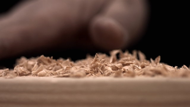 Hand brusing off wood shavings, slow motion