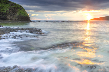 Natural green moss at beach rock with cloudy sunset background